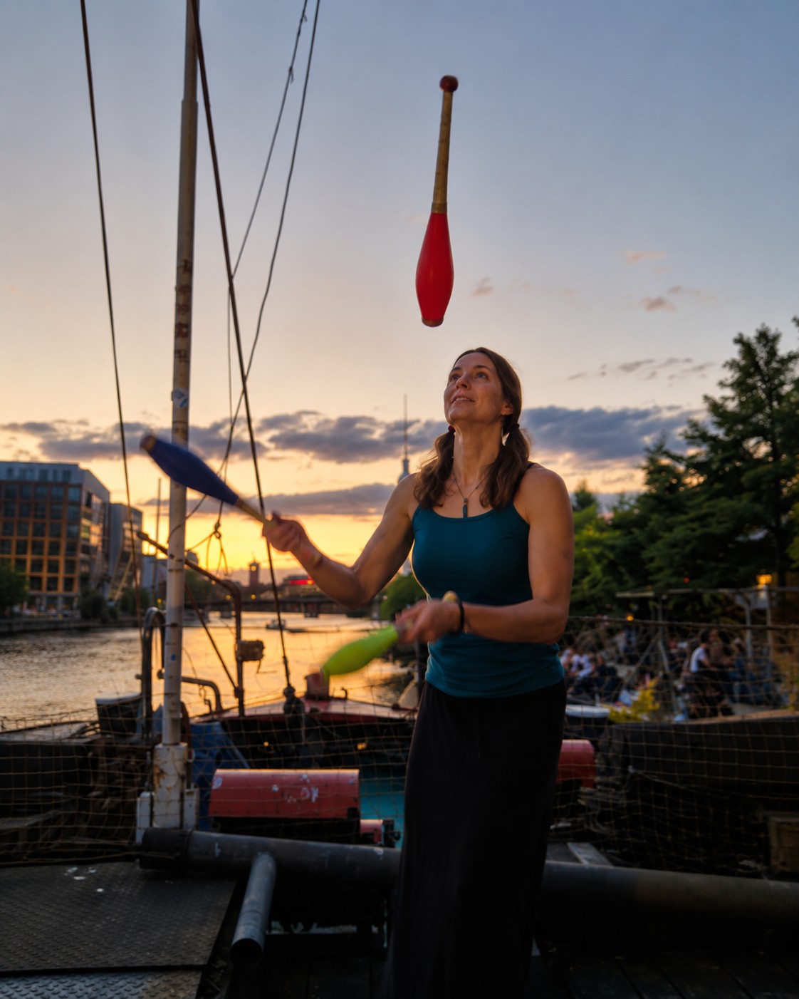 Diana S. Engelhard juggling clubs aboard a boat at sunset.